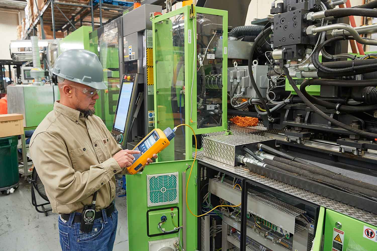Technician in hard hat uses a Fluke Networks Versiv to test industrial machinery